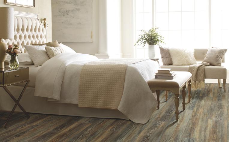 Wood look flooring in bedroom with white bedding and cream colored decor.